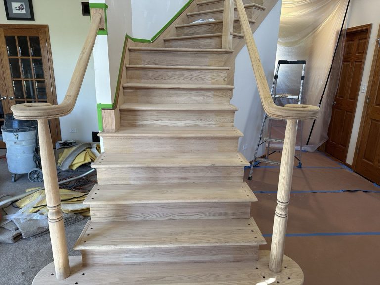 An unfinished oak staircase with a light wood handrail and bare steps