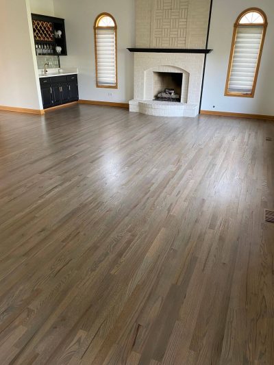 A room with refinished hardwood floors, a sink and a fireplace