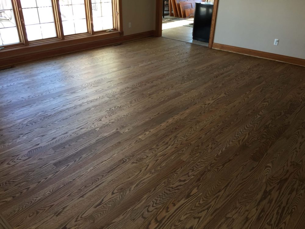 Sunlit living room with midtone oak hardwood floor and large windows