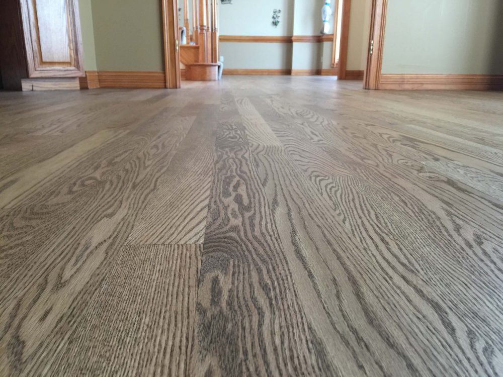 Low-angle view of light Rubio Monocoat hardwood floor with wood trim in entry area