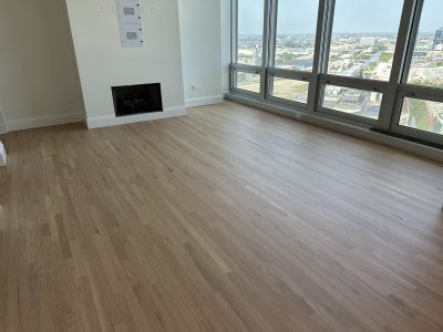 Refinished red oak floors in living room with large windows and even, light tone