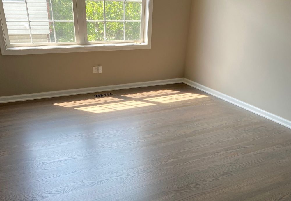 Empty bedroom with new oak hardwood flooring installed, shows the finished result after replacing carpet with hardwood