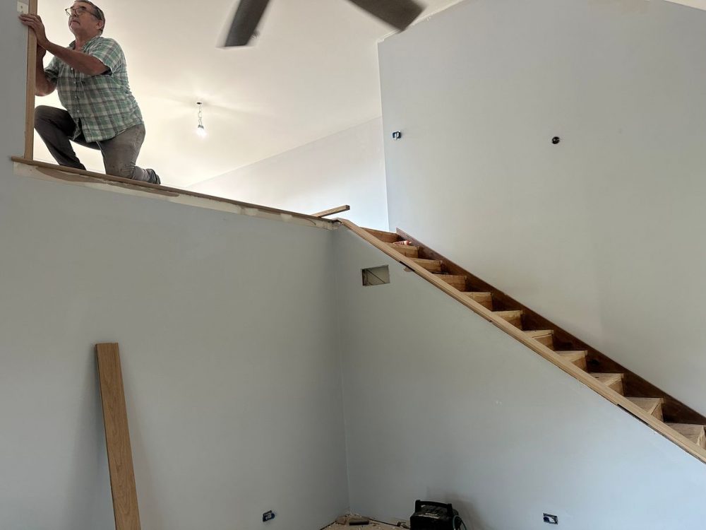 Installing a new white oak handrail during stair installation