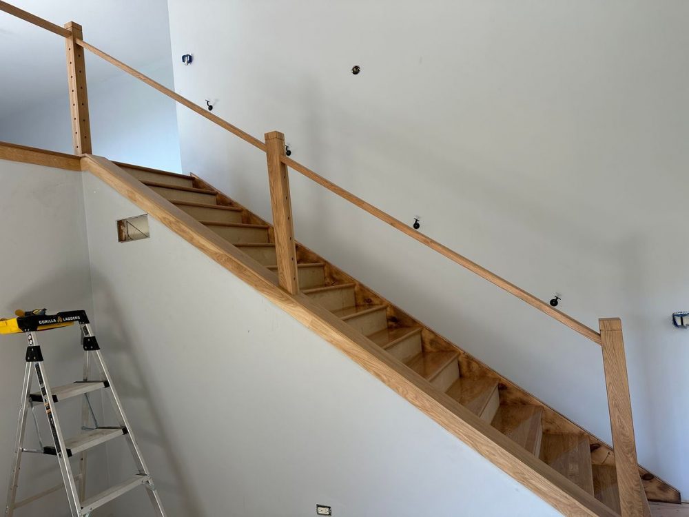Before staircase remodel: traditional wood balusters and handrail on an open stair run during a full home rehab in West Chicago, IL.