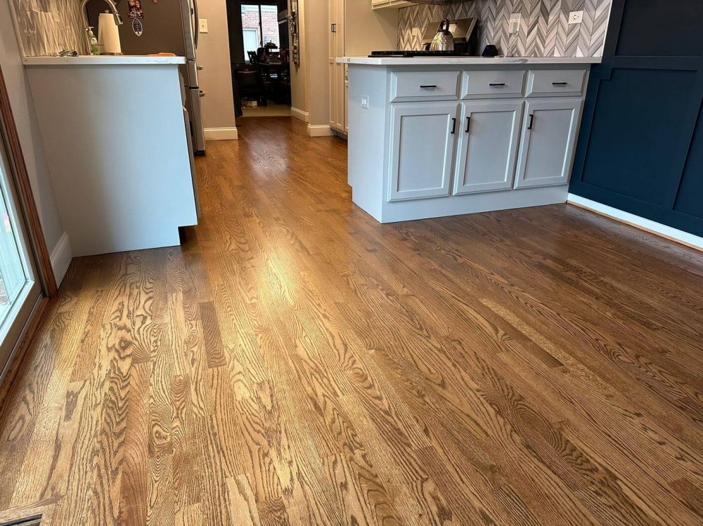Alt: Wide after view of refinished oak floors in an open kitchen and dining layout