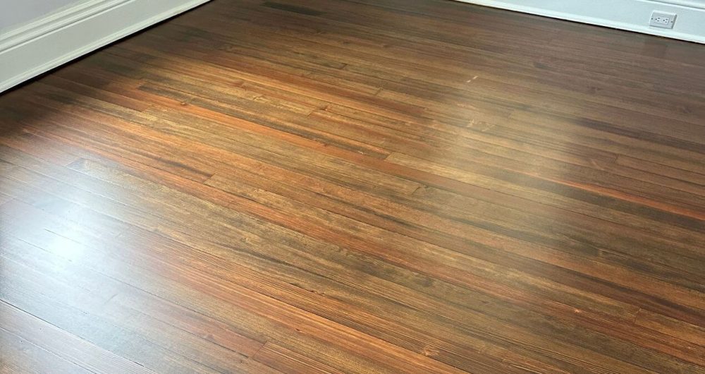 Dark-stained pine floor with long straight grain and visible board-to-board color variation, a look often associated with older homes and softer wood floors
