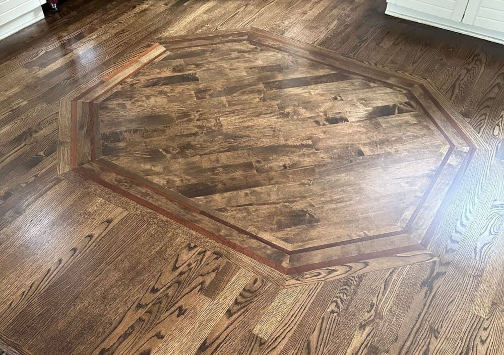 Dark red oak floor with a custom octagonal inlay in the center, highlighting the stronger oak grain and the decorative look possible with stained hardwood flooring
