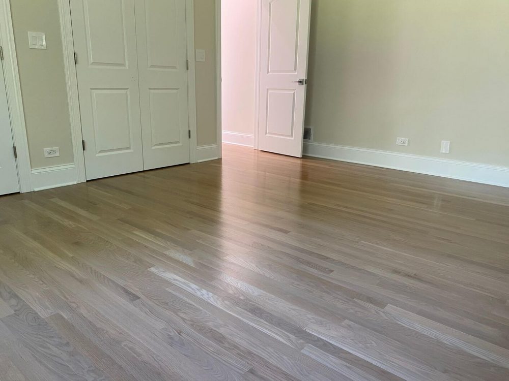 Light white oak hardwood floor in a bedroom, with pale color, gentle grain movement, and the balanced look that makes white oak a common choice for modern interiors