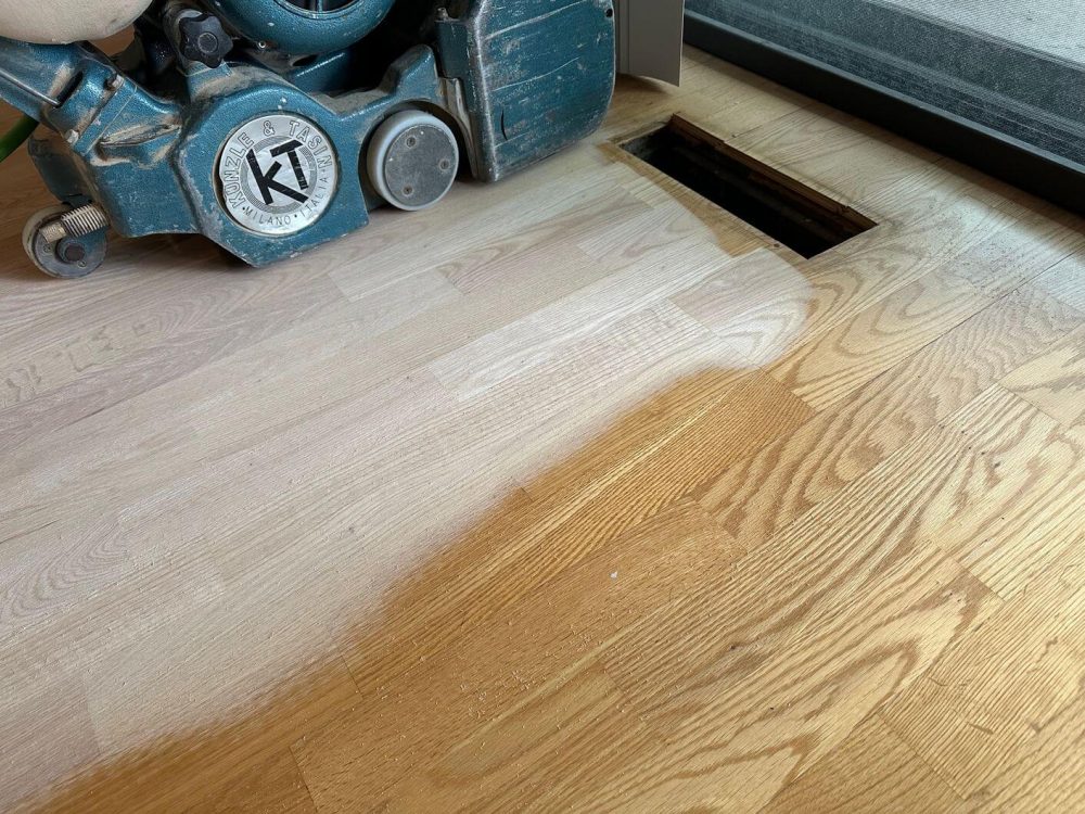 Our team carefully sanding the floating engineered white oak floor in this Burr Ridge condo during the refinishing process.