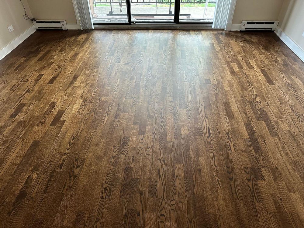 The finished engineered white oak floor after our refinishing work shows a rich Espresso color and a clean matte look near the patio doors.