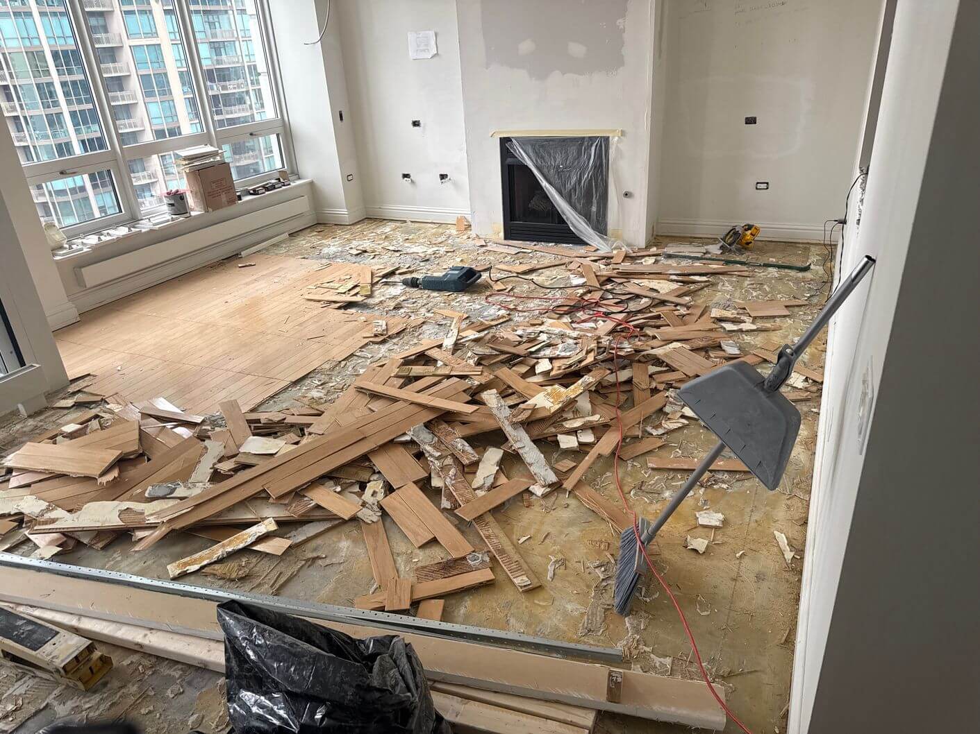 Old glued-down engineered hardwood being removed from the concrete floor during demolition in the Downtown Chicago condo.