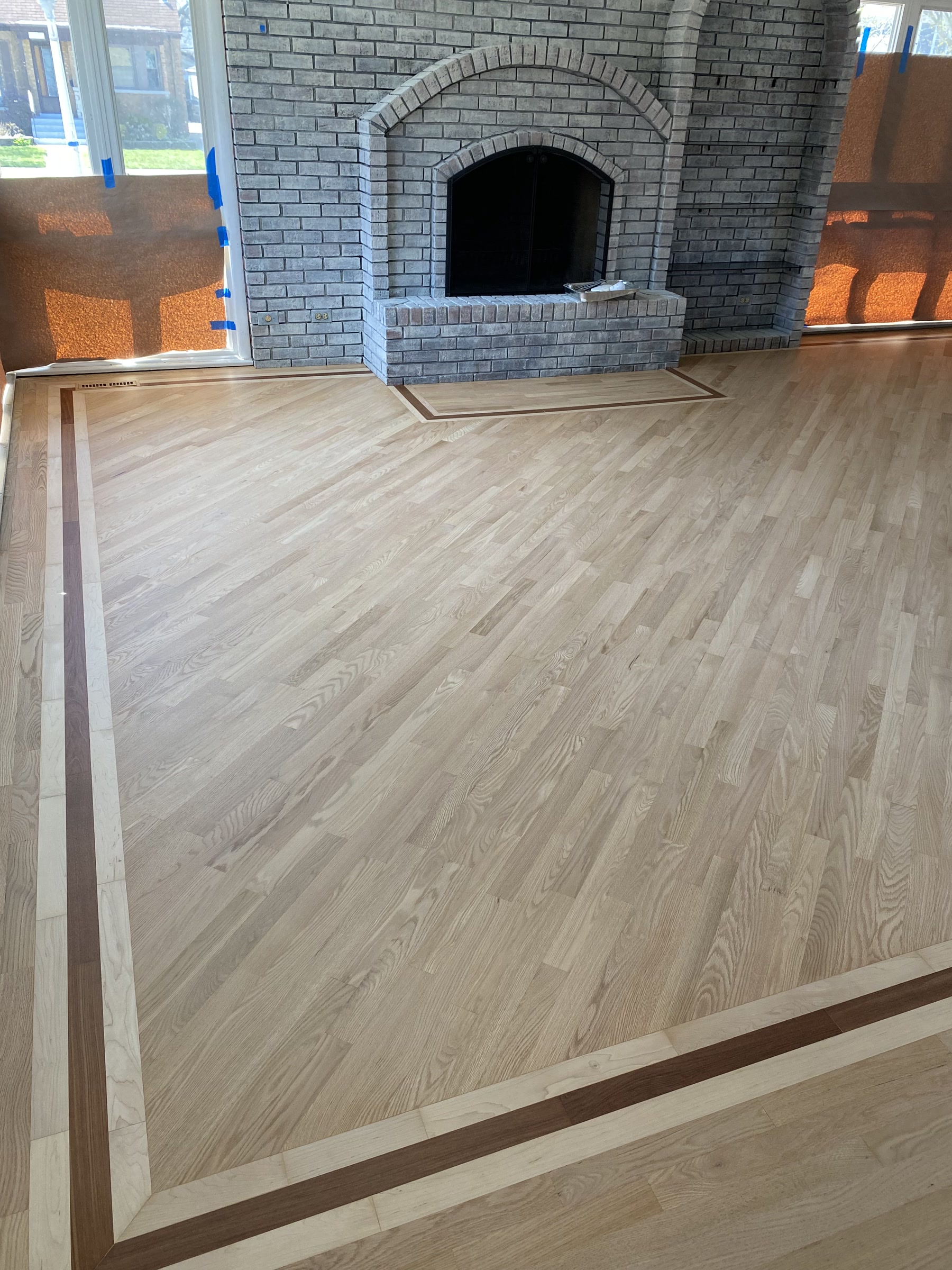 Refinished natural hardwood floor with a dark border by the fireplace, West Chicago, IL