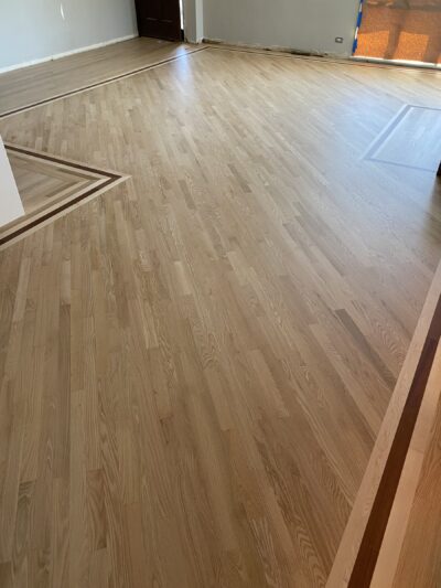 Natural hardwood floor with a border transition in the empty room, West Chicago, IL