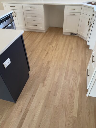 Natural hardwood floor in the kitchen with white cabinets and a dark island, West Chicago, IL
