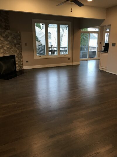 Custom greige hardwood floor in the living room with a stone fireplace, Western Springs, IL