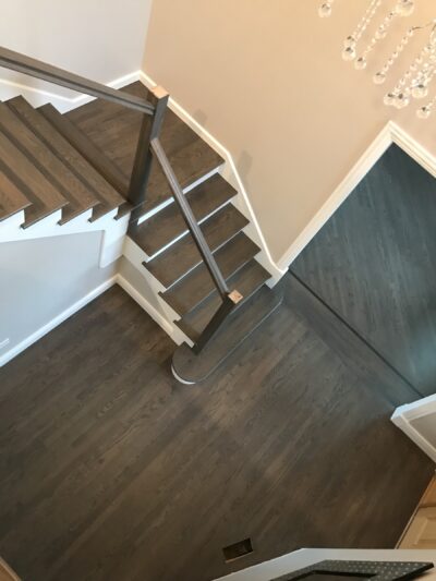 Modern staircase with a horizontal metal railing over greige hardwood, Western Springs, IL