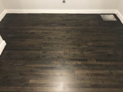 Ebony-stained hardwood floor in a clean room with white baseboards, Wheaton, IL