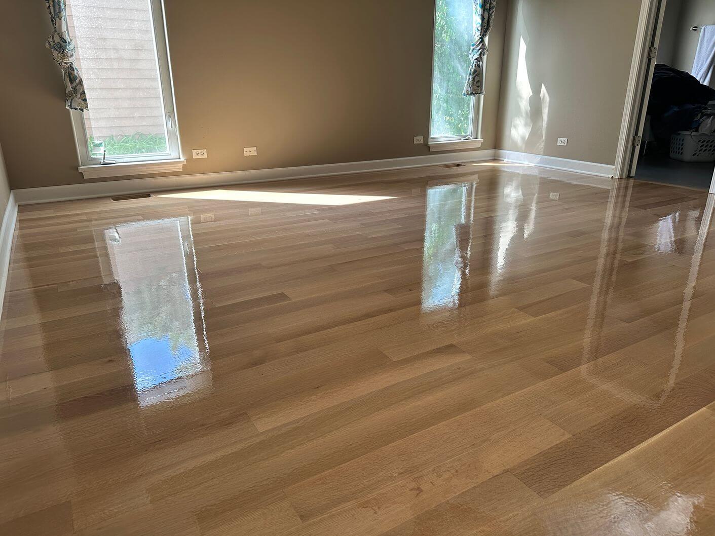 Freshly coated rift and quartered white oak flooring reflecting the windows during the finishing process.