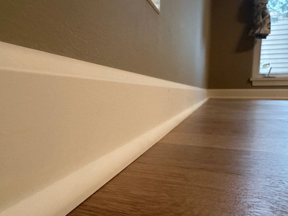 New white baseboard and base shoe installed along the finished white oak flooring.