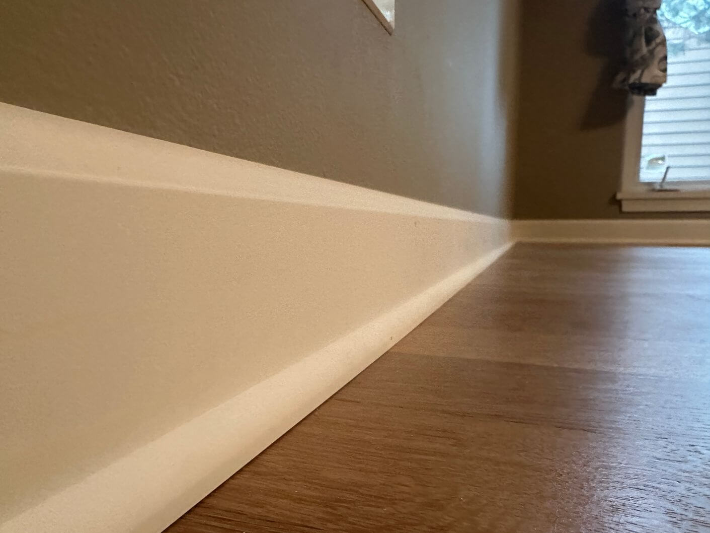 New white baseboard and base shoe installed along the finished white oak flooring.