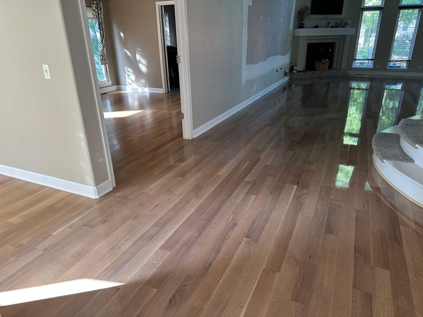 White oak flooring during finish application, showing the transition between freshly coated and completed areas.