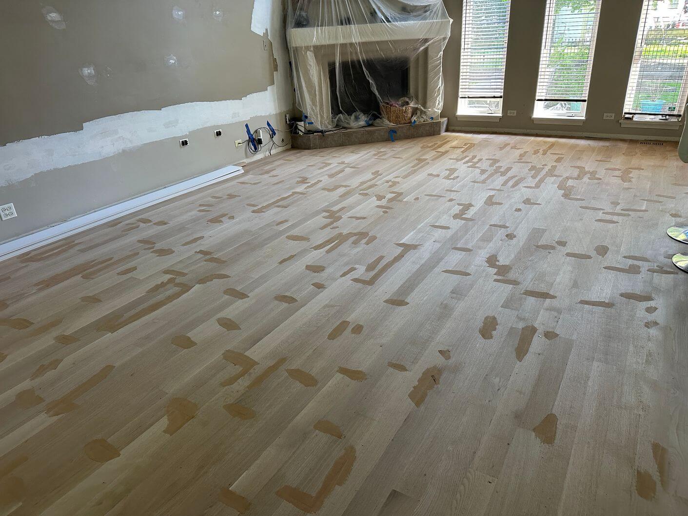 Wood filler applied across the sanded white oak floor to address joints and surface imperfections before finishing.