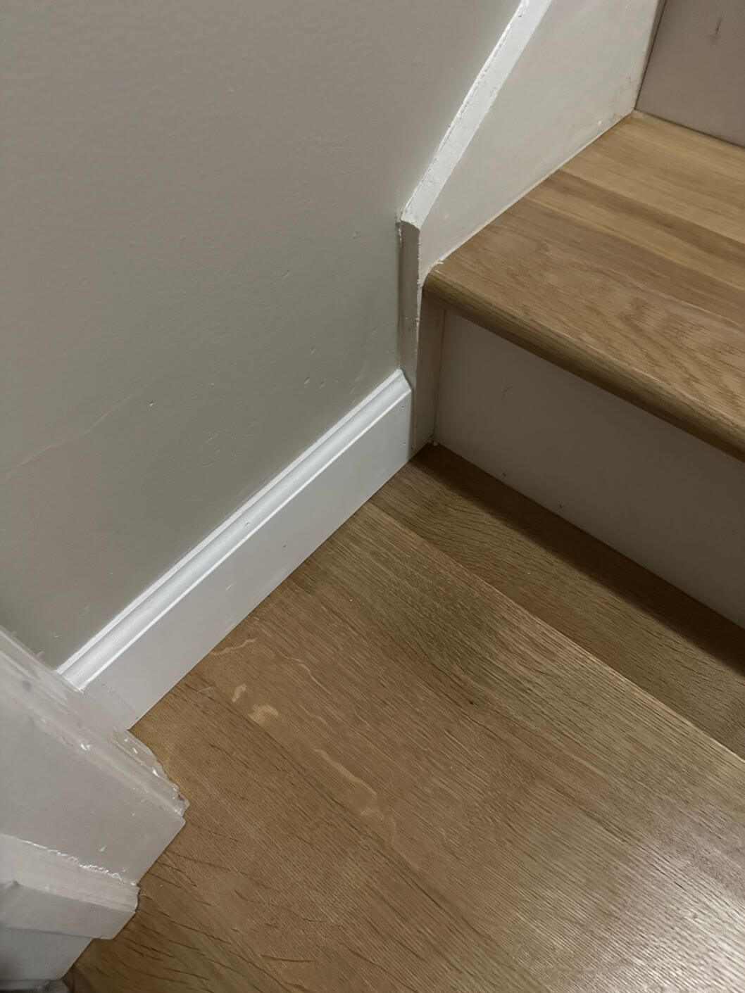 Close-up of the natural white oak floor meeting the staircase after installation and finishing.