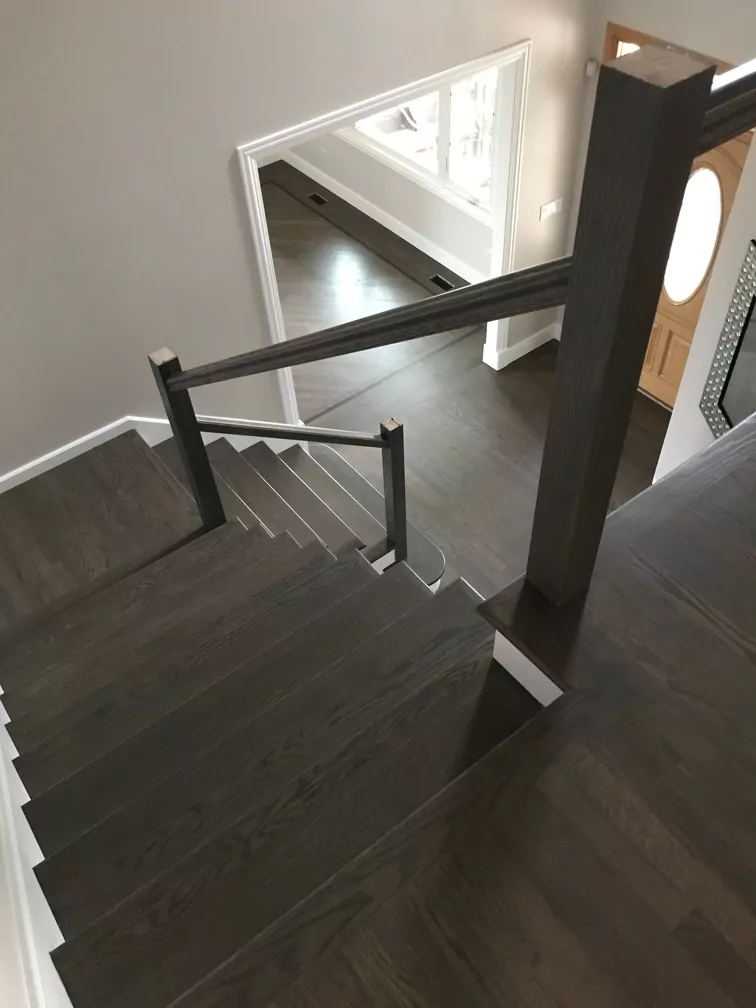 Dark wooden staircase with modern railing and polished flooring