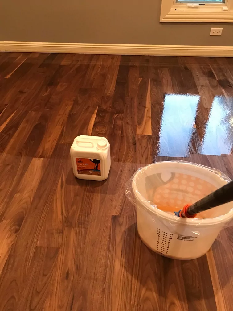 Wood floor being refinished with water-based products in a bucket
