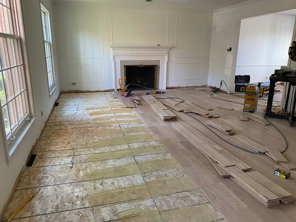 Hardwood floor installation process in a room with a fireplace