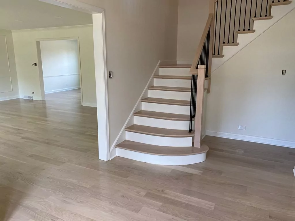 Room with stairs and light hardwood after refinishing