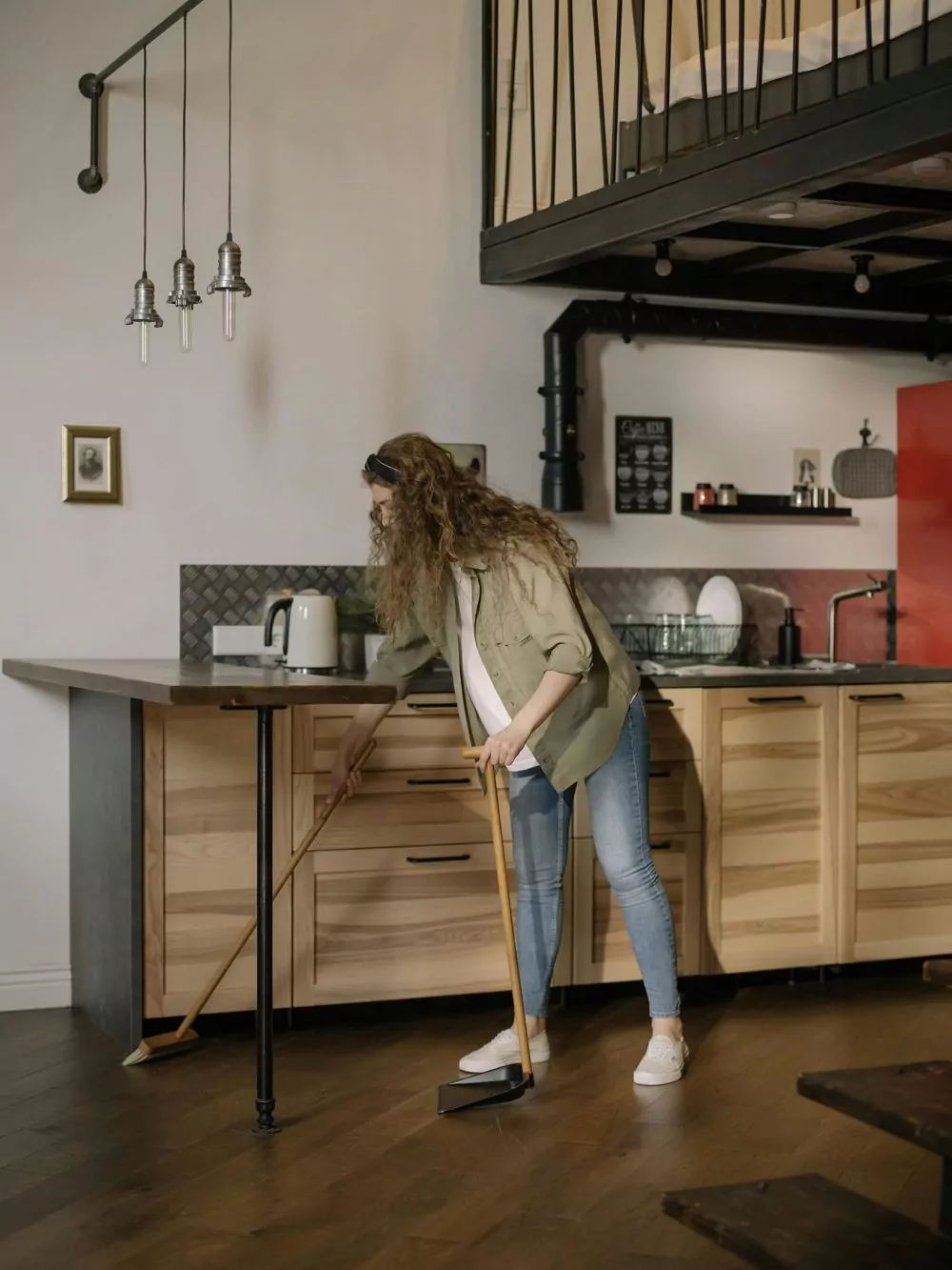 A lady sweeping a hardwood floor before polishing it.