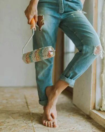 Person holding a paint roller ready to start a DIY interior remodeling project.