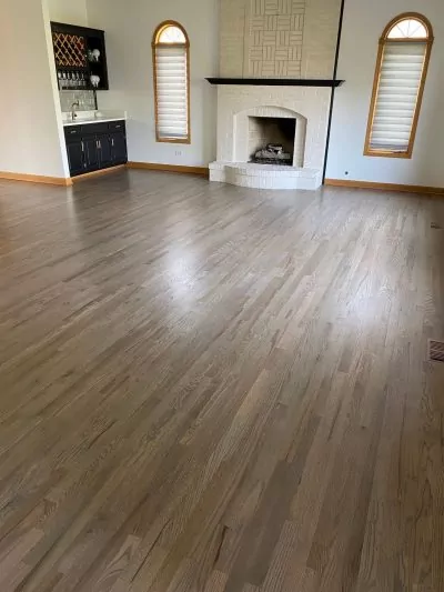 A room with refinished hardwood floors, a sink and a fireplace