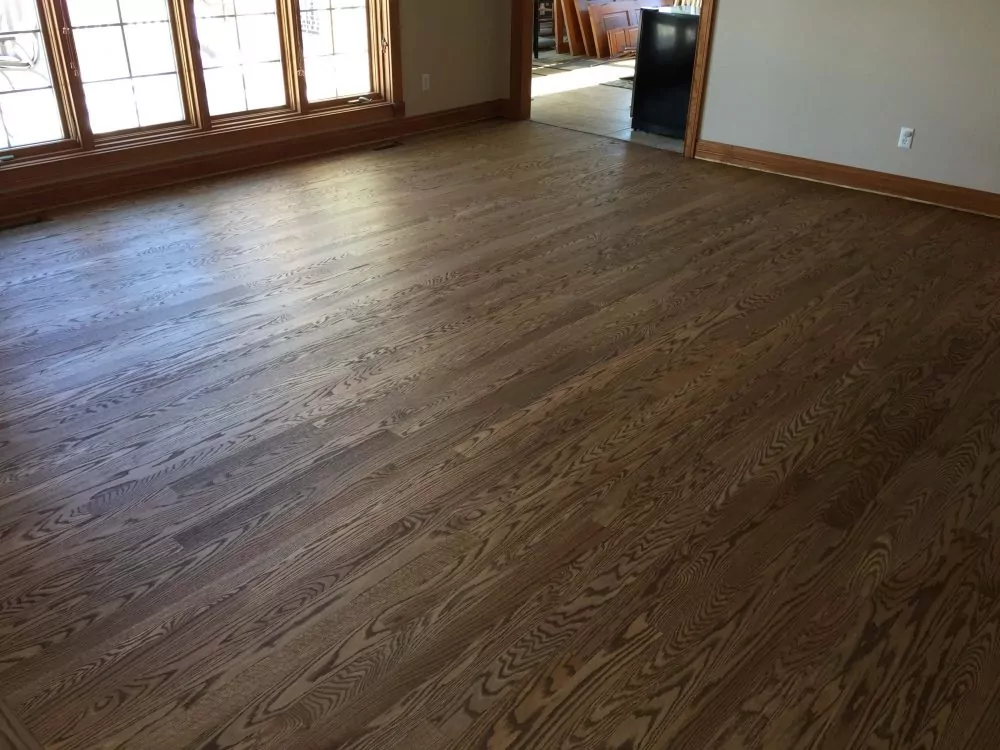 Sunlit living room with midtone oak hardwood floor and large windows