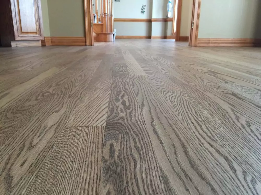 Low-angle view of light Rubio Monocoat hardwood floor with wood trim in entry area