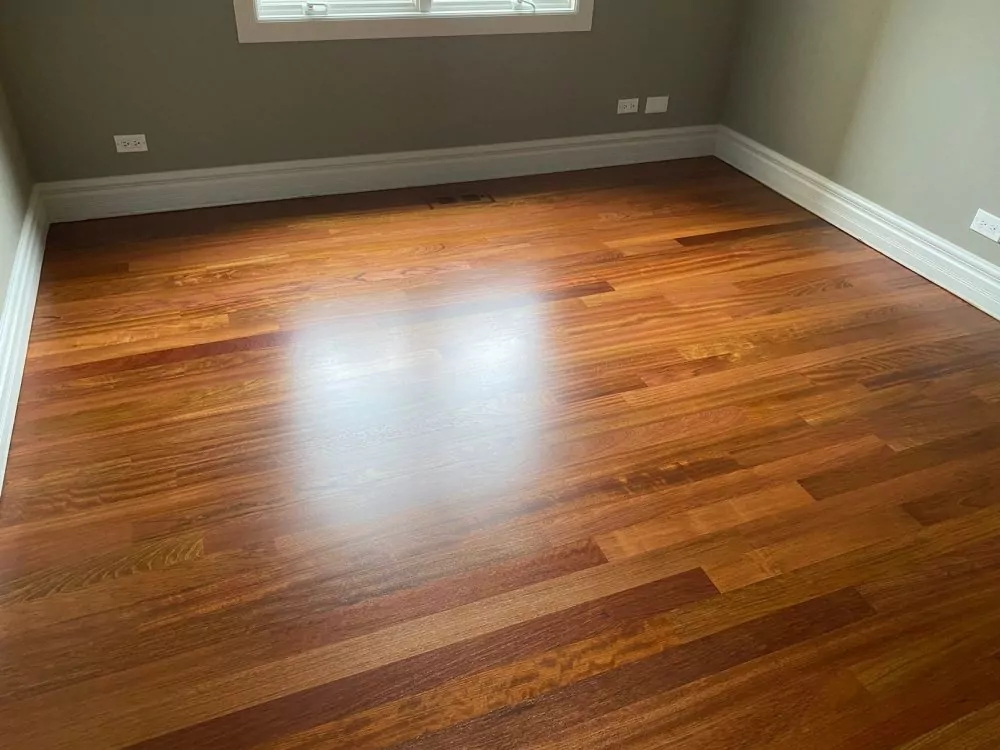 Finished hardwood floor with warm stain in a bedroom, shows the visual payoff that drives many carpet-to-hardwood upgrades