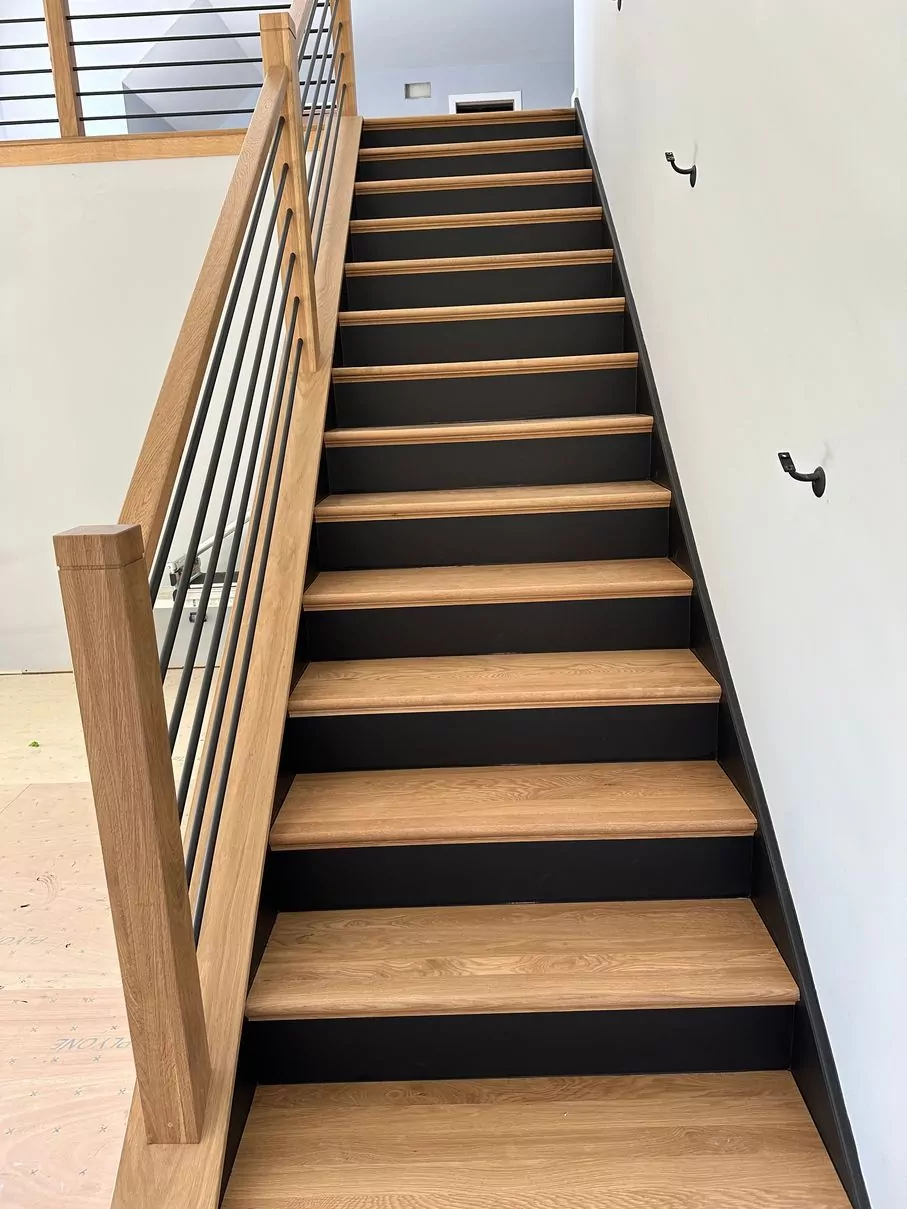 White oak stair treads with black-painted risers and clean modern railing after a staircase remodel