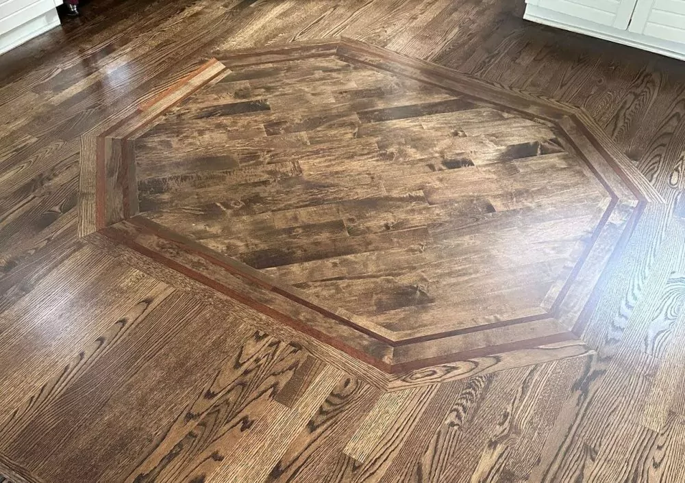 Dark red oak floor with a custom octagonal inlay in the center, highlighting the stronger oak grain and the decorative look possible with stained hardwood flooring